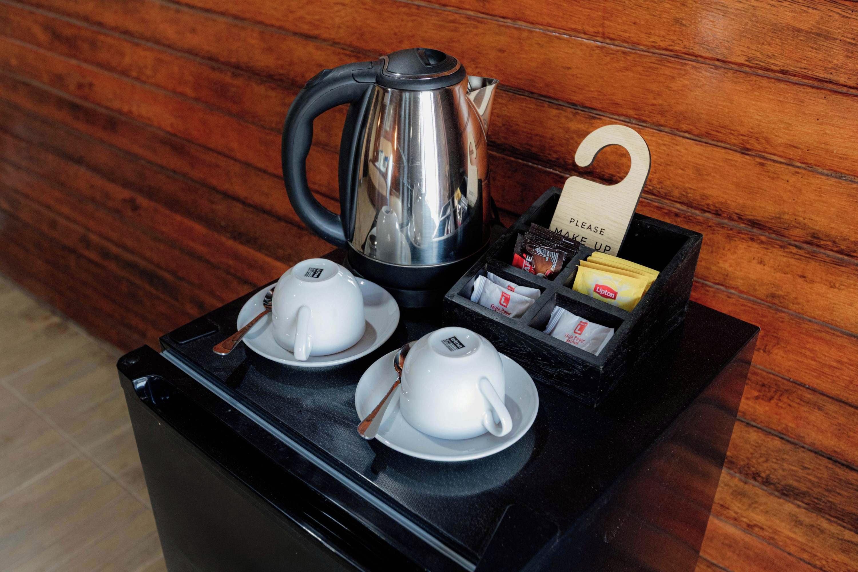 A coffee station with a kettle, two cups, and a box of Lipton tea bags.