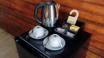 A coffee station with a kettle, two cups, and a box of Lipton tea bags.