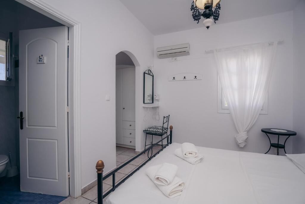 Un dormitorio con una cama, una mesita de noche, una silla, un espejo y un equipo de aire acondicionado.