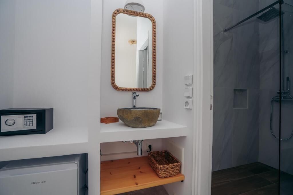 Un baño con estante de madera, lavamanos de piedra, espejo y cabina de ducha.