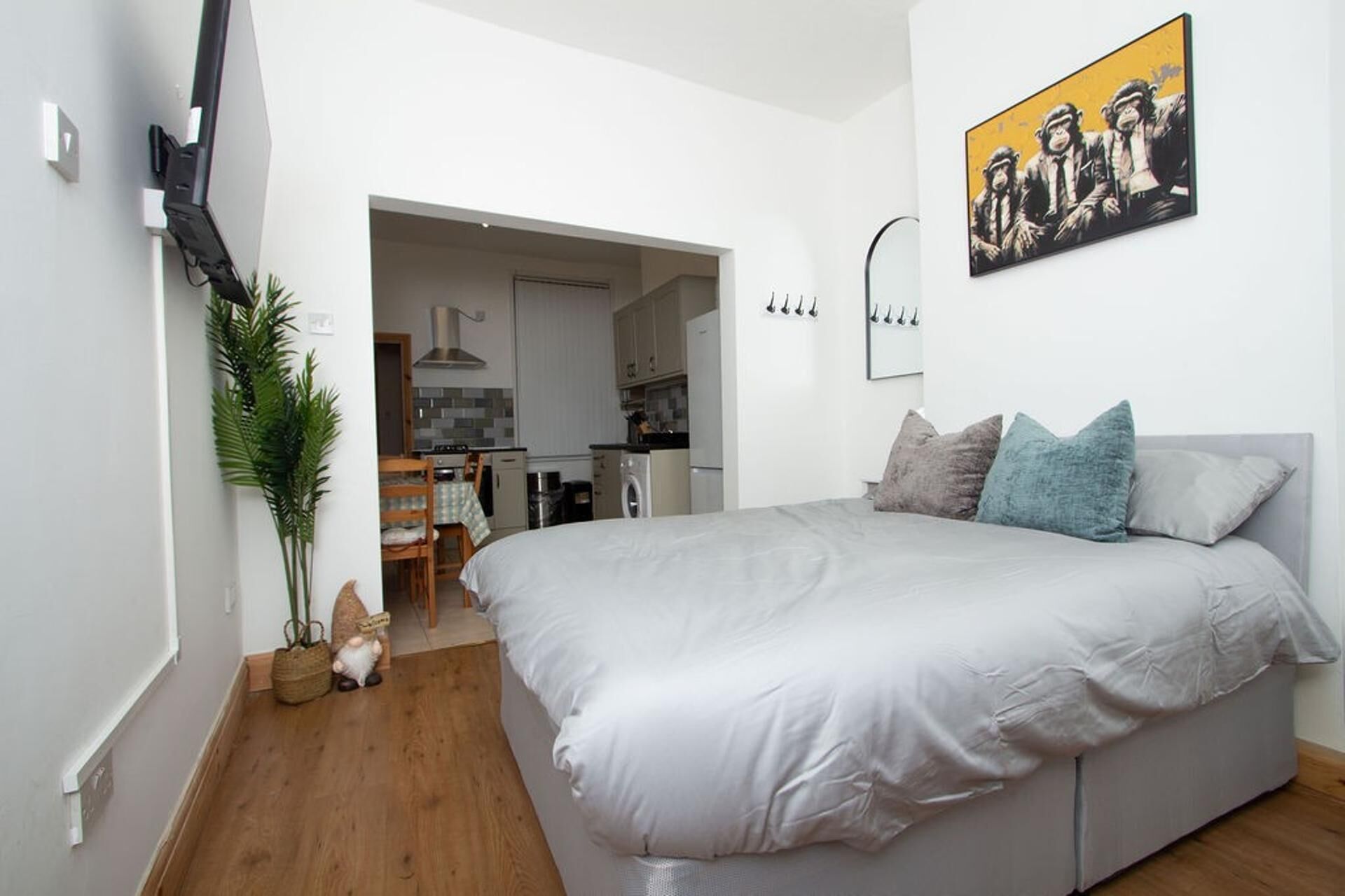 A bedroom with a bed, pillows, a wall-mounted light fixture, and a painting.