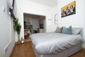 Un dormitorio con una cama, almohadas, una lámpara de pared y un cuadro.