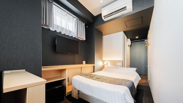A hotel room with a bed, a desk, a TV, and an air conditioning unit. - FL Residence Jingugyoen VI (Shibuya City)