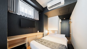 A hotel room with a bed, a desk, a flat-screen TV mounted on the wall, and an air conditioning unit. - FL Residence Jingugyoen VI (Shibuya City)