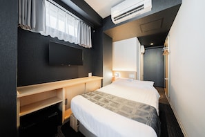 A hotel room with a bed, a desk, a flat-screen TV mounted on the wall, and an air conditioning unit. - FL Residence Jingugyoen VI (Shibuya City)