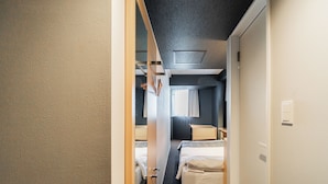 A narrow corridor leading to a room with a bed, a small table, and a window with curtains. - FL Residence Jingugyoen VI (Shibuya City)