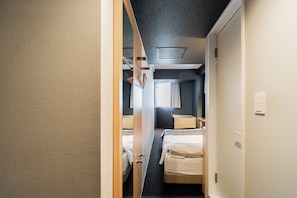 A narrow corridor leading to a room with a bed, a small table, and a window with curtains. - FL Residence Jingugyoen VI (Shibuya City)