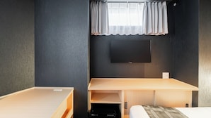 A compact hotel room with a single bed, a desk, and a television mounted on the wall. - FL Residence Jingugyoen VI (Shibuya City)