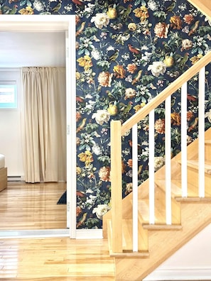 Eine Treppe mit hölzernen Geländern und floraler Tapete.