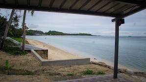A beach with a concrete viewing platform, palm trees, and a clear view of the water. - Beachfront home with beautiful sunset views. Must see! (Asan)
