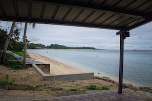 A beach with a concrete viewing platform, palm trees, and a clear view of the water. - Beachfront home with beautiful sunset views. Must see! (Asan)