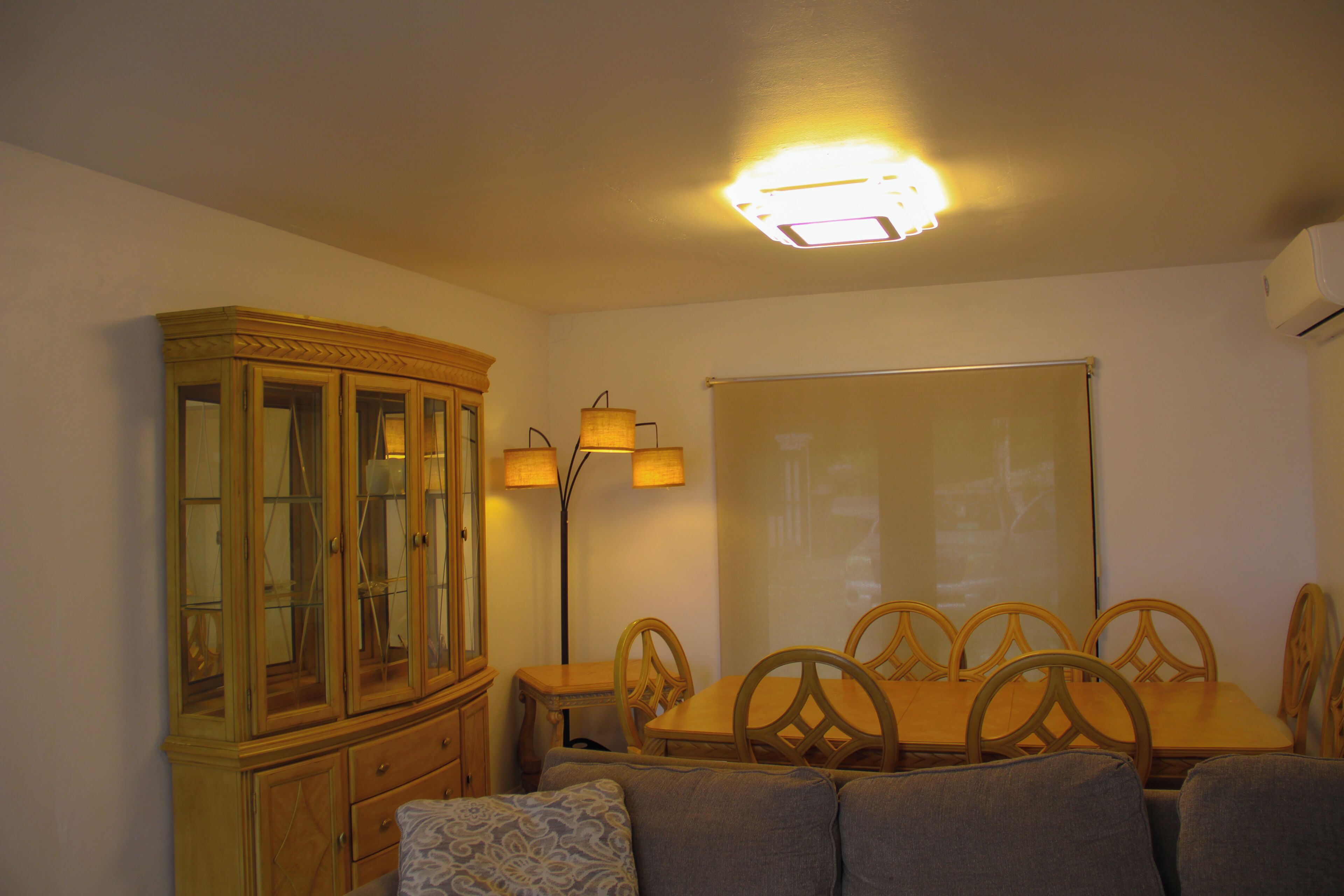 Un coin repas comprenant un buffet en bois, une table avec des chaises et un luminaire suspendu au plafond.