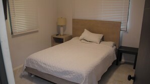 A bedroom with a bed, a nightstand, a lamp, and a door. - Beachfront home with beautiful sunset views. Must see! (Asan)