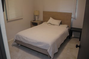 A bedroom with a bed, a nightstand, a lamp, and a door. - Beachfront home with beautiful sunset views. Must see! (Asan)