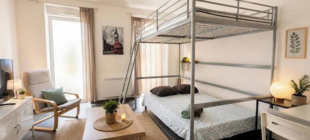 A bunk bed room with a desk, chair, and a plant.