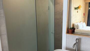 Ein modernes Badezimmer mit einer Duschkabine aus Glas, einem weißen Waschbecken mit einem Einhebelhahn und einer Holzwaschkommode.