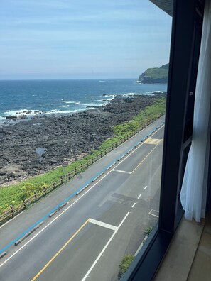 A coastal road with a rocky shoreline, a clear sky, and a view of the ocean.