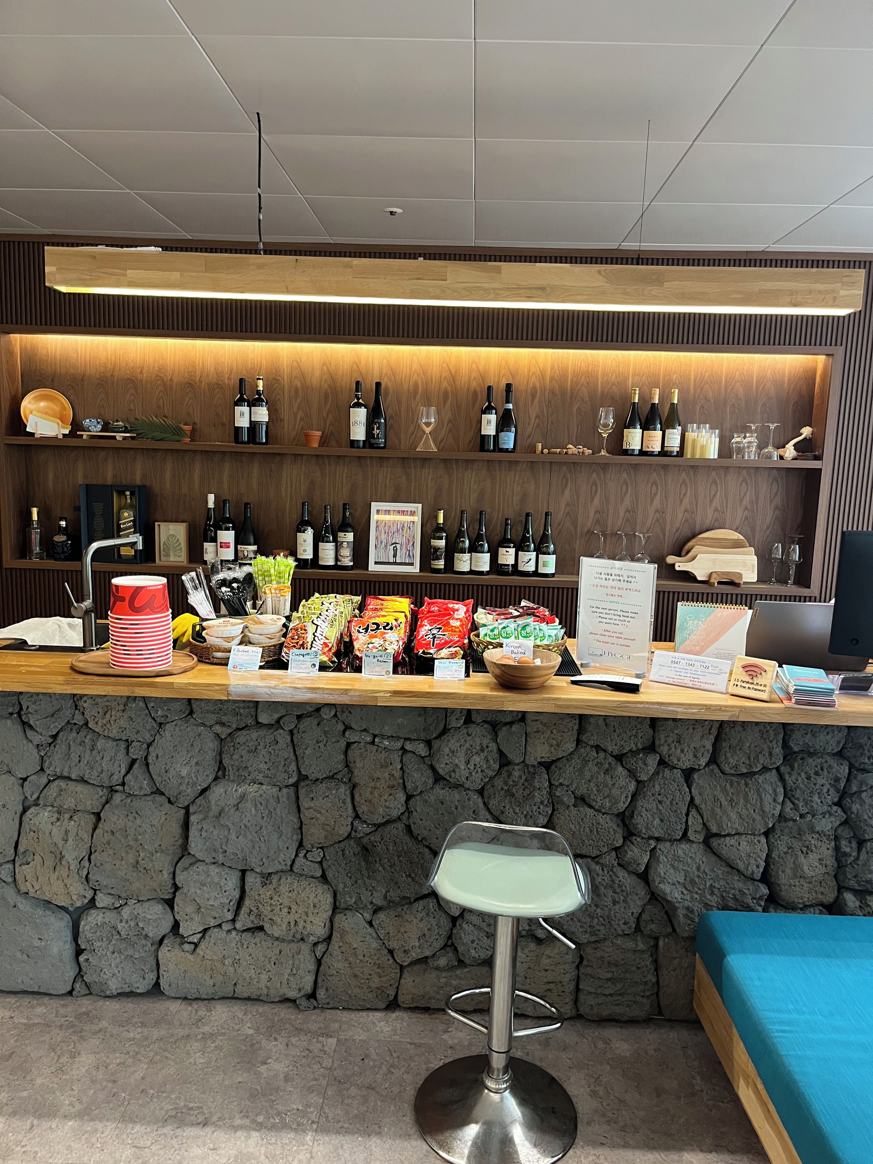 A bar area with a stone counter, a stool, and a couch.
