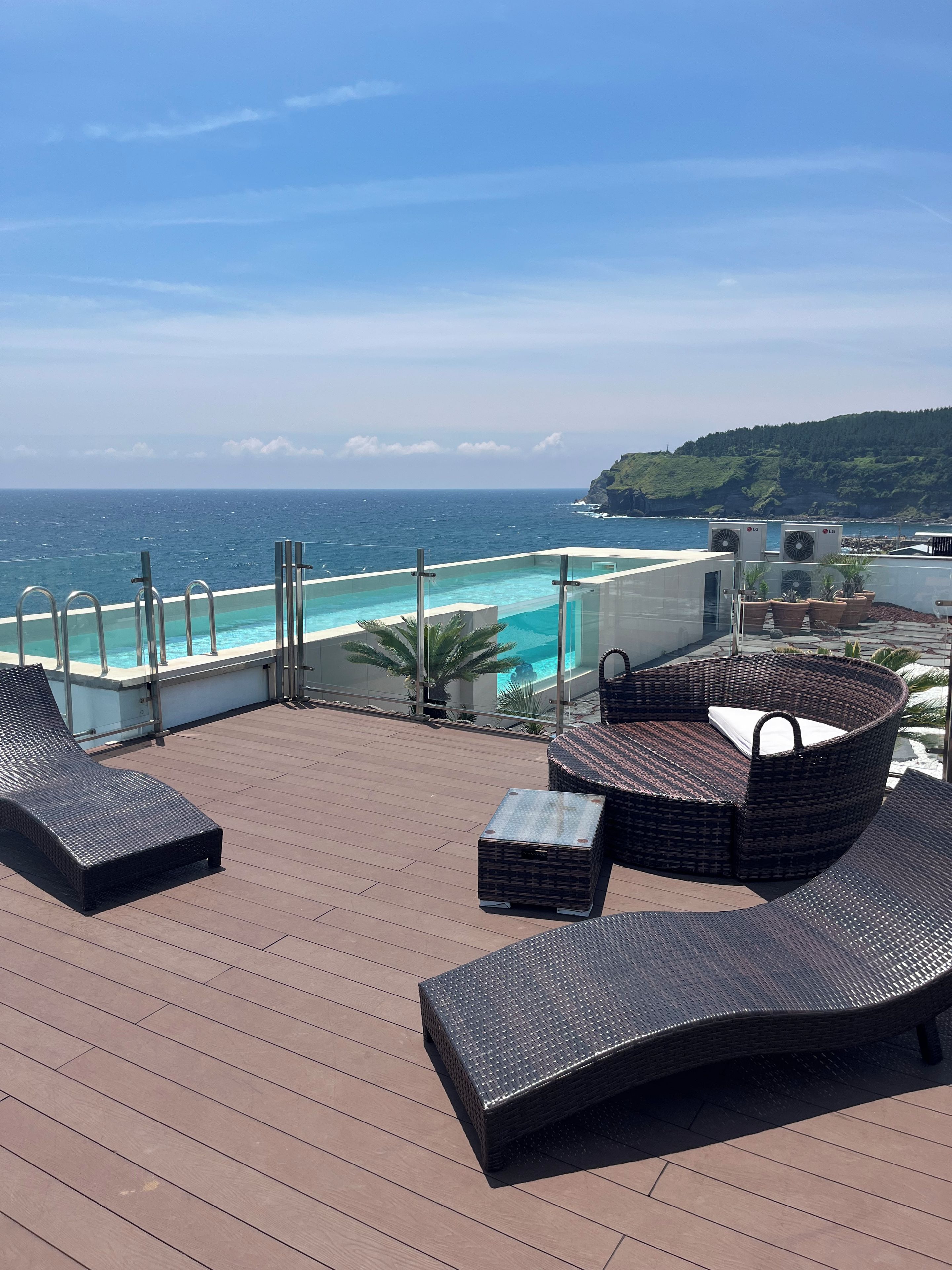 Una terraza en la azotea con piscina, sillas de descanso y vistas al océano.