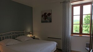 Ein Schlafzimmer mit einem Bett, einem Nachttisch, einem Heizkörper und einem Fenster mit Vorhängen.