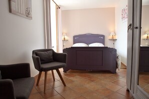 Un dormitorio con cama, dos lámparas de noche, una silla y una puerta.