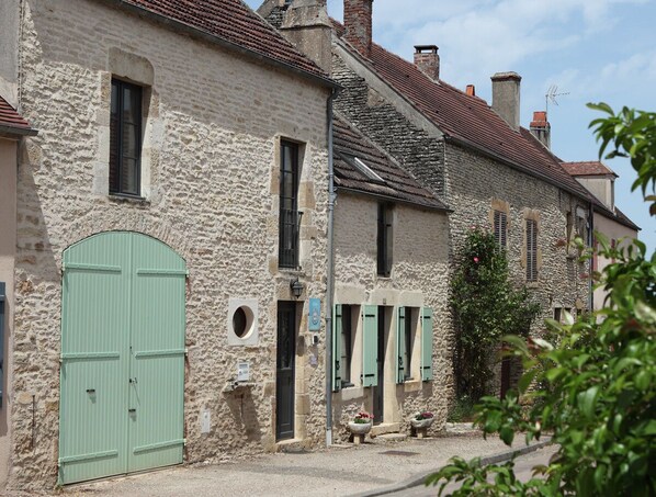 A row of stone buildings with green shutters and a green door.