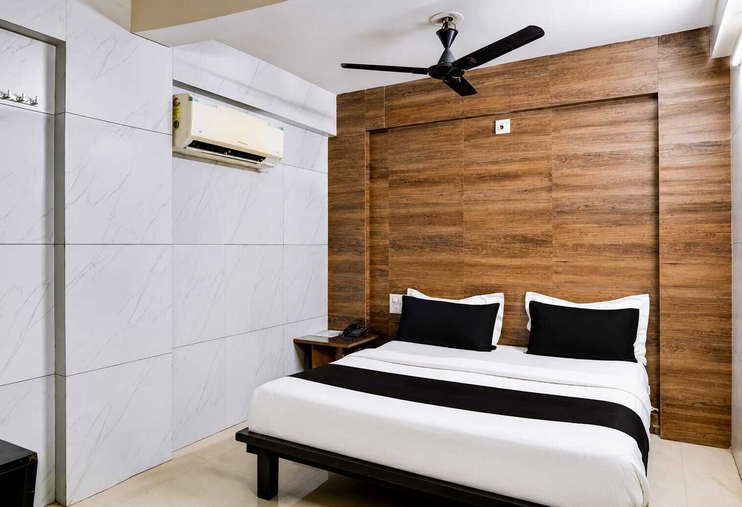 A modern hotel room with a bed, a nightstand, a telephone, and a ceiling fan.
