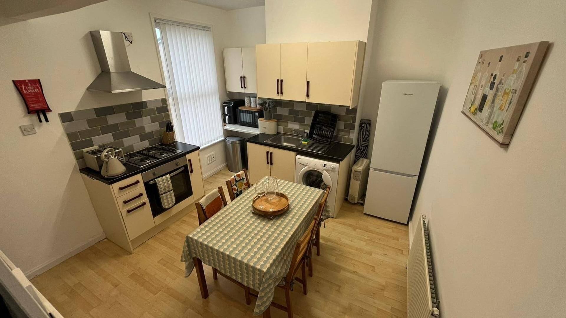A compact kitchen with a dining table, a stove, a microwave, and a refrigerator.