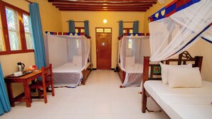 A room with two beds, a wooden table, and a chair. - Bustani Oasis with AC,Pool, Family-Friendly, Couples, Beach 5 Min Walk (Nungwi)