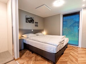A bedroom with a bed, bedside tables, a wall-mounted artwork, and a window with blinds. - Modern Waterfront Villa Retreat for 4 (Wanneperveen)