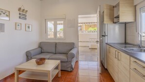 A compact living space with a kitchenette, a sofa, a table with a bowl, and a window with a view of the outside. - CHL Casa El Remo mar y Tranquilidad en La Palma (Los Llanos de Aridane)