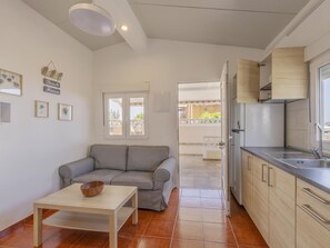 A compact living space with a kitchenette, a sofa, a table with a bowl, and a window with a view of the outside. - CHL Casa El Remo mar y Tranquilidad en La Palma (Los Llanos de Aridane)