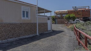 A building with a stone facade, a covered entrance, and a vehicle parked in front. - CHL Casa El Remo mar y Tranquilidad en La Palma (Los Llanos de Aridane)