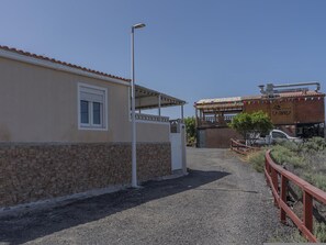 A building with a stone facade, a covered entrance, and a vehicle parked in front. - CHL Casa El Remo mar y Tranquilidad en La Palma (Los Llanos de Aridane)