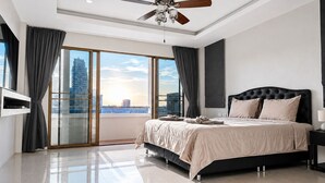 Een moderne slaapkamer met een groot bed, een plafondventilator en uitzicht op de stad.