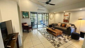 A living room with a sofa, armchair, coffee table, and a television.