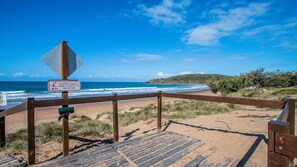 A wooden boardwalk leading to a beach with a sign indicating kitesurfing permitted north of Sandcastles Beach Access.