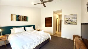 Ein Hotelzimmer mit einem Bett, einem Deckenventilator, einem Gemälde und einer Tür zu einem Badezimmer.