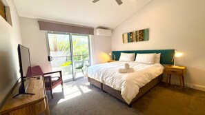 A bedroom with a bed, bedside tables, a desk, a chair, and a view of the outdoors.