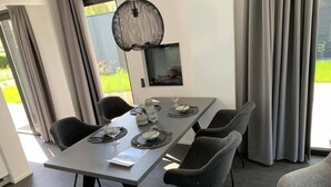 Ein Essbereich mit einem langen Tisch, sechs Stühlen und einem an der Wand befestigten Fernseher.