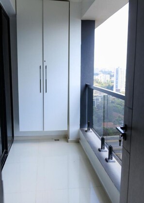 A balcony with a view of a cityscape, a white wardrobe, and a door with a key lock. - Charming apartment in an enchanting Nairobi neighborhood perfect for your stay (Nairobi)