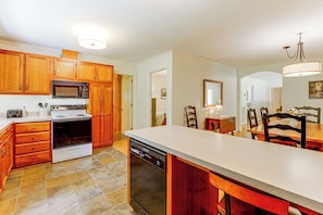 A kitchen with wooden cabinets, a built-in microwave, stove, and dishwasher. - Creekside Cottage: Kayak, Tube, Fish, Remote Work (Dugspur)
