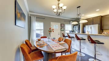 A modern kitchen with a central island, bar stools, and pendant lighting.