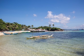 A beach with clear water, boats, and a building with a red roof. - Paradise Ocean View Boracay (Malay)