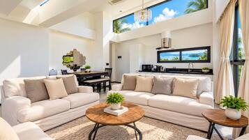 A spacious living area with a large sofa set, a coffee table, and a dining table.