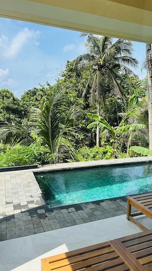 A pool area with a tiled deck, surrounded by lush greenery and palm trees. - Paradise Ocean View Boracay (Malay)