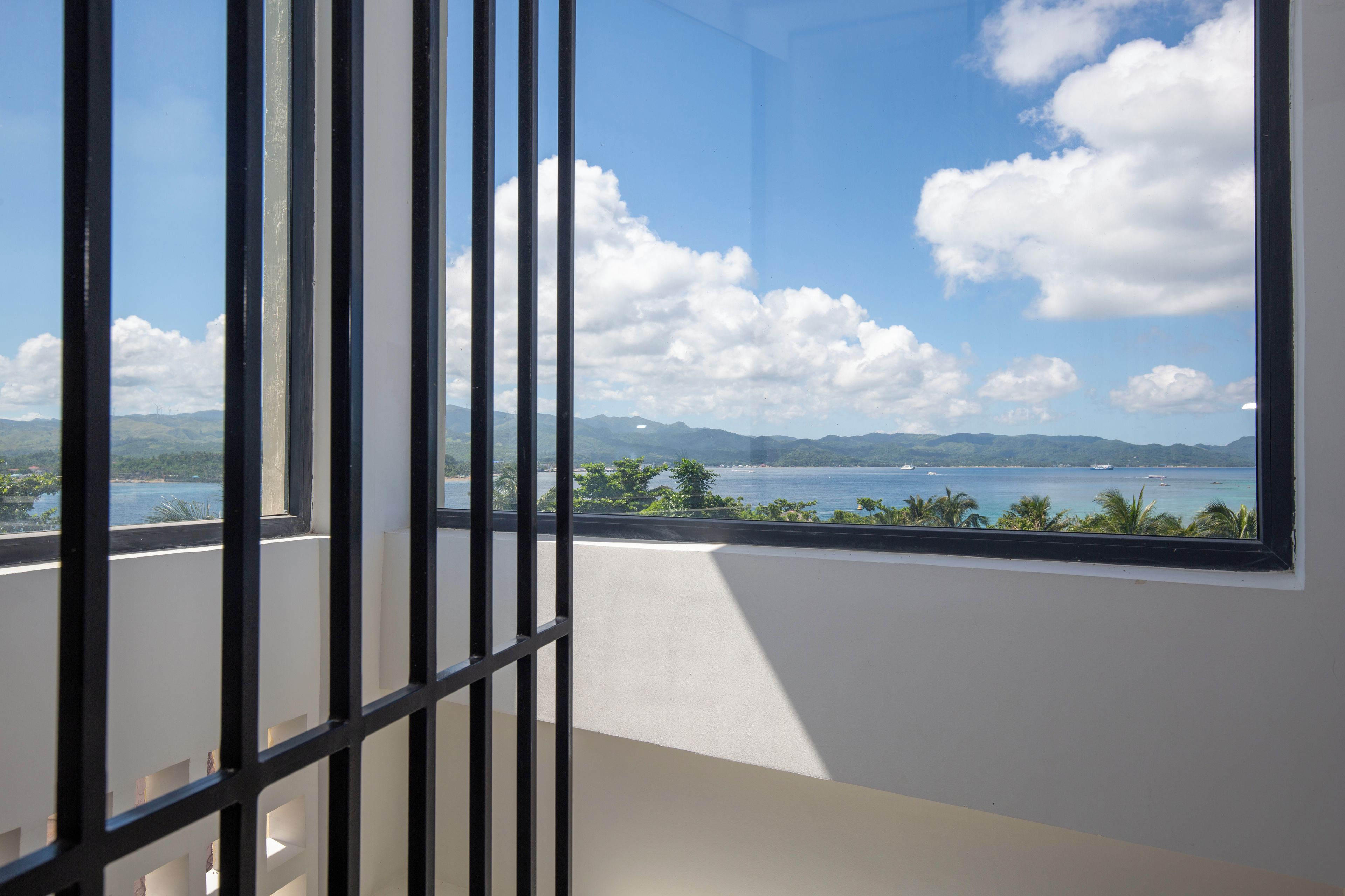 A room with a large window overlooking a body of water and distant mountains.