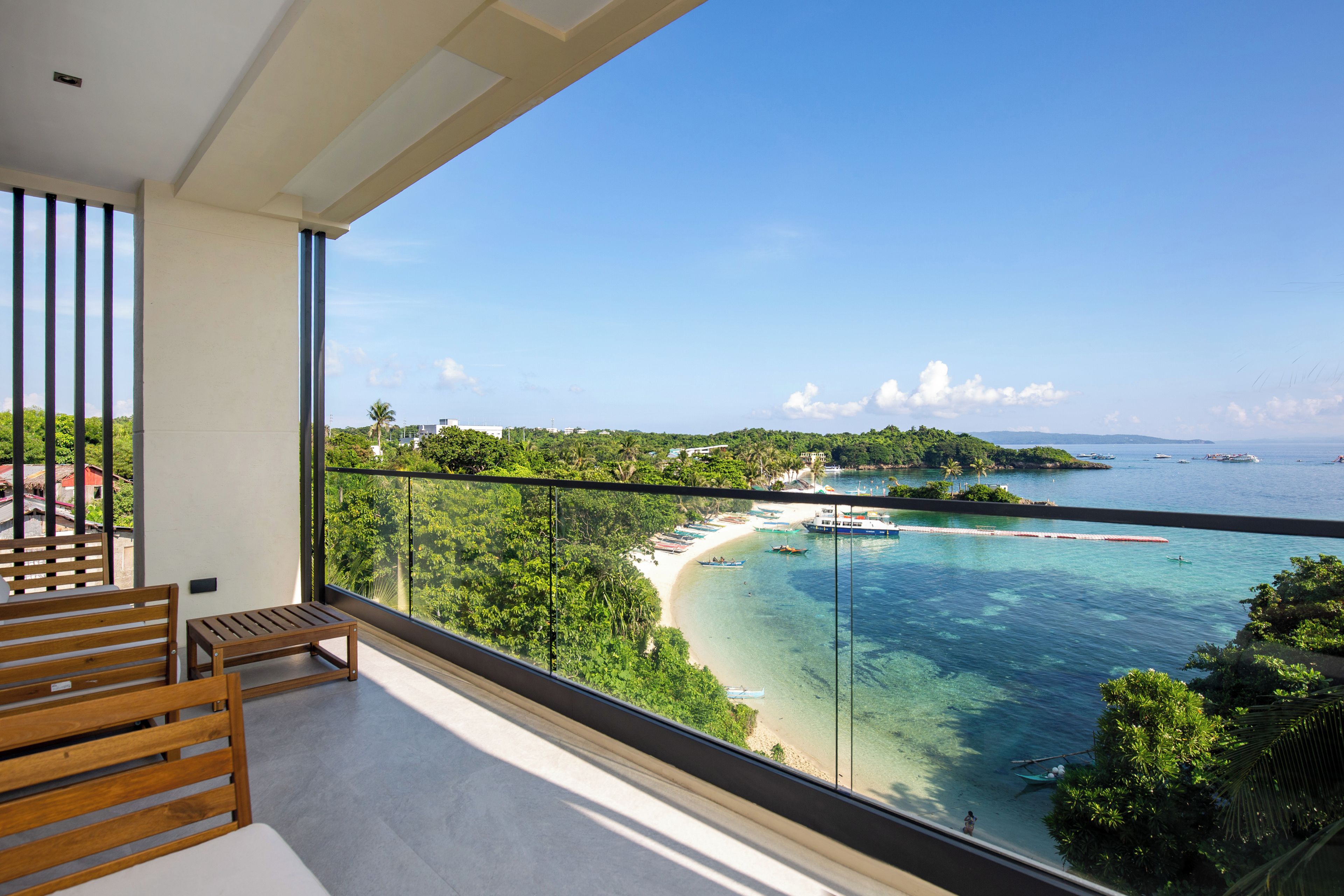 A balcony with a view of a beach and clear blue sea.