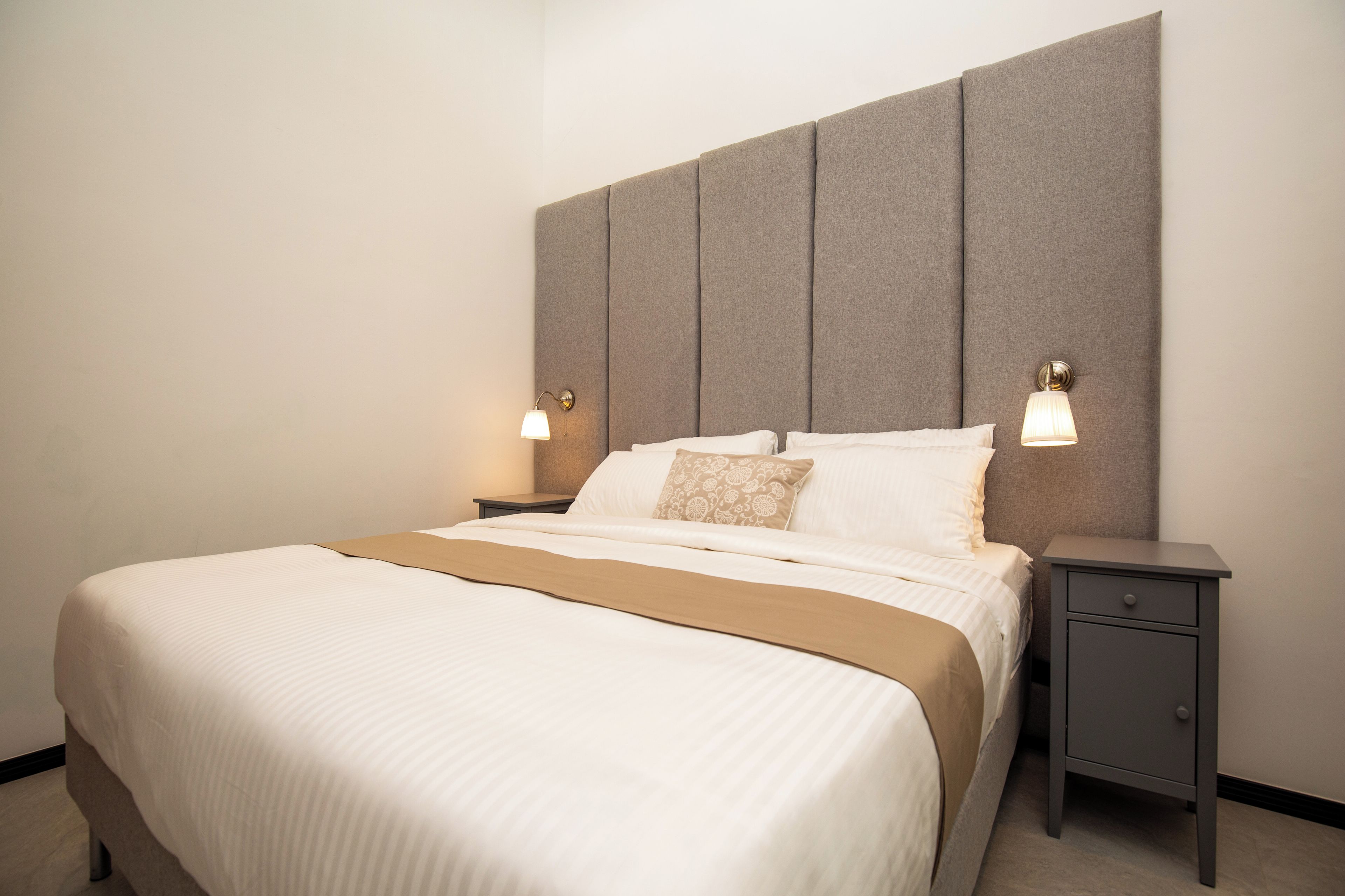 A hotel room with a large bed, two bedside tables, and a headboard.