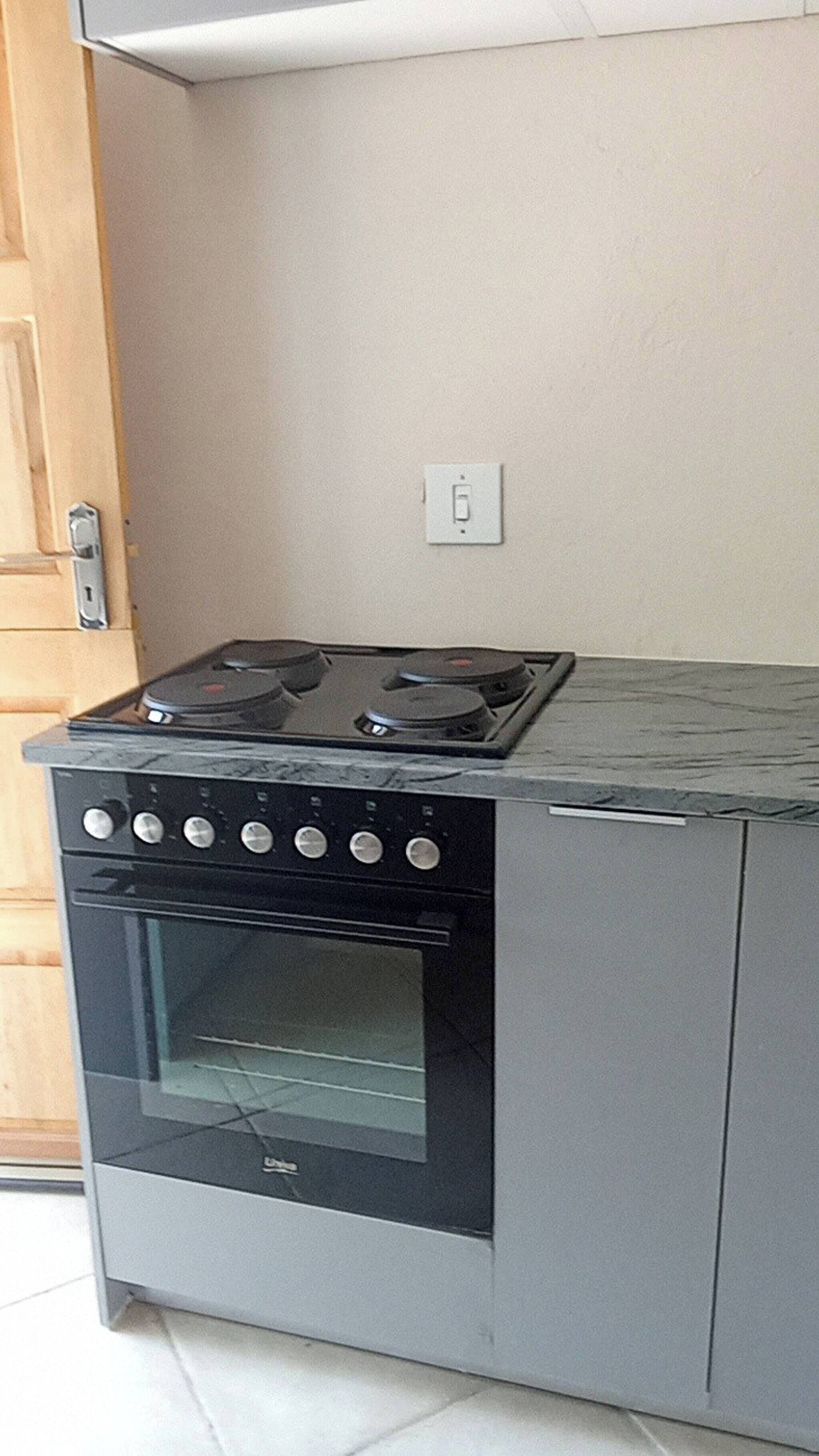 A compact kitchen with a stove, oven, and a single electrical outlet on the wall.